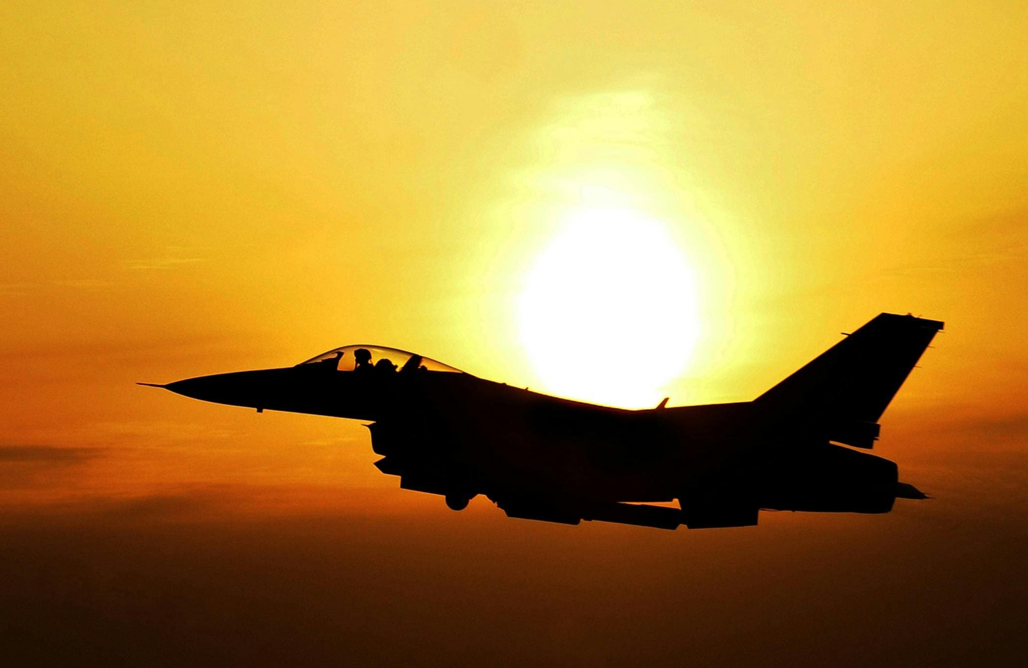 fighter jet silhouette against setting sun
